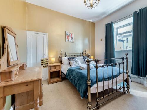 a bedroom with a bed and a desk and a window at Nelson Cottage in Tenby