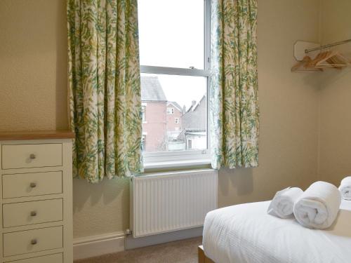 a bedroom with a bed and a window with curtains at Beachcomber Corner in Lytham St Annes
