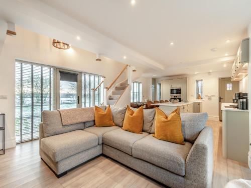 ein Wohnzimmer mit einem grauen Sofa und orangefarbenen Kissen in der Unterkunft Forge Cottage in Liverton