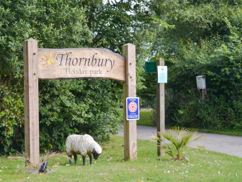 a sheep grazing in the grass next to a sign at Willow in Thornbury