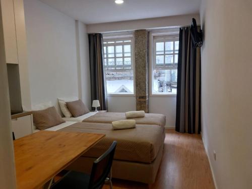 a bedroom with two beds and a table and a window at São Marcos Apartaments in Braga
