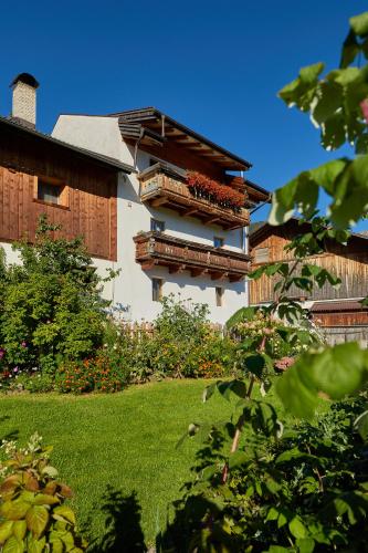 a building with two balconies and a yard with flowers at Pfitscherhof in Campo di Trens