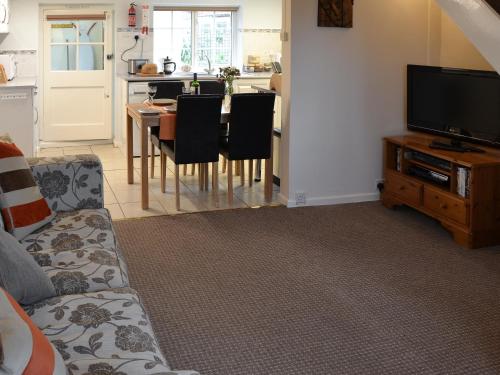 ein Wohnzimmer mit einer Couch und einem Tisch mit Stühlen in der Unterkunft Glen Cottage in Yaxham