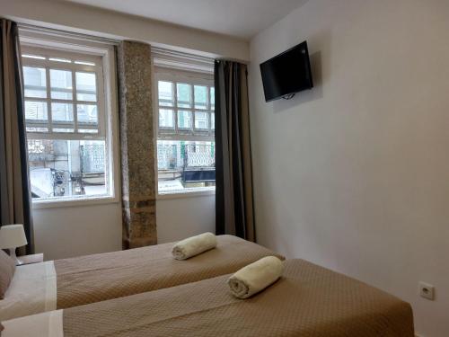 a bedroom with two beds and a tv and a window at São Marcos Apartaments in Braga