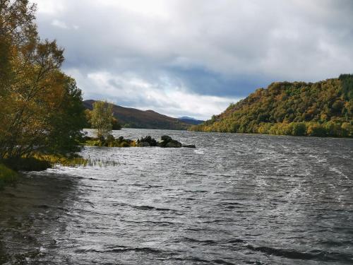 a view of a river with trees on the shore at The Grain Store in Aberarder