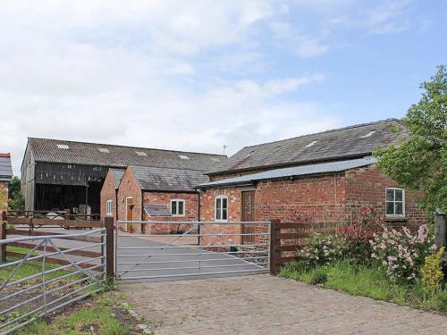 a brick barn with a gate in front of it at The Shippon in Burscough