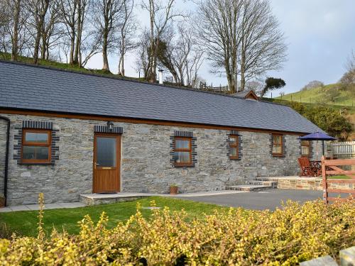a stone house with a grass yard in front of it at Eithinog in Talybont