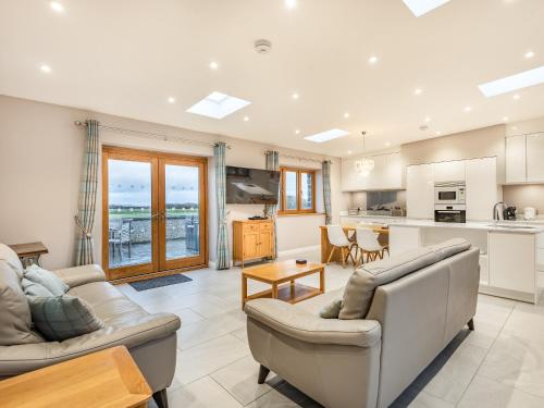 a living room with two couches and a kitchen at Primrose Cottage in Holyhead
