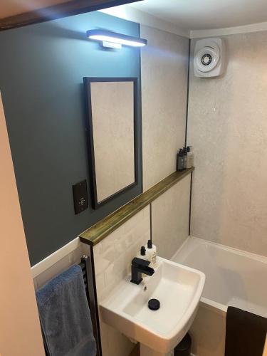 a bathroom with a sink and a mirror and a tub at Charming cozy cottage in Guisborough in Guisborough