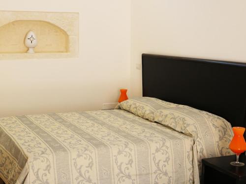 un letto in una camera da letto con due vasi arancioni su un tavolo di La Trottoria Agriturismo a Otranto