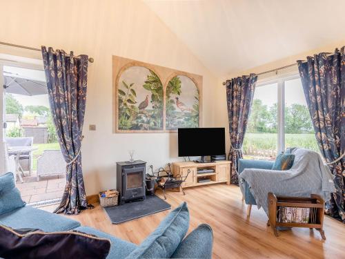 a living room with a tv and some chairs at Violet Cottage in Credenhill