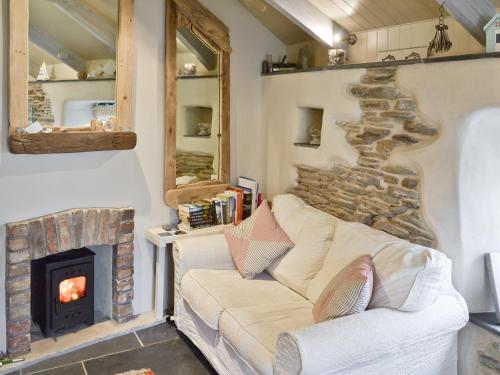 Una sala de estar con un sofá y una chimenea. en Driftwood, en Newquay