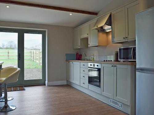 a kitchen with white cabinets and a large window at Wagtail Cottage in Foxton