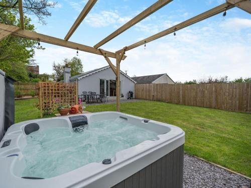 a hot tub in a backyard with a pergola at Briar Cottage in Great Eccleston