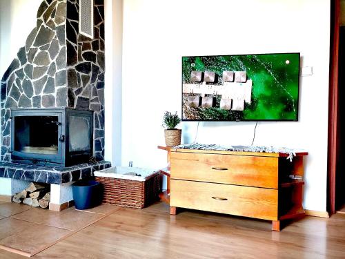 a living room with a fireplace and a dresser with a television at Eternity Chalet Trnovec in Liptovský Trnovec