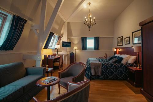 a hotel room with a bed and a couch at Grand Hotel en Résidence De Draak in Bergen op Zoom