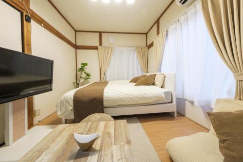 a bedroom with a bed and a tv in a room at Quiet 1K Full Room, Serta Queen Bed, Good to Shinjyuku & Ikebukuro, Belluna Dome, 201 in Tokorozawa