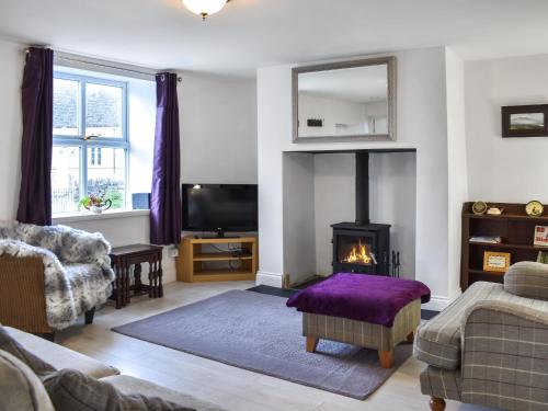 a living room with a fireplace and a tv at The Old Cottage in Coanwood