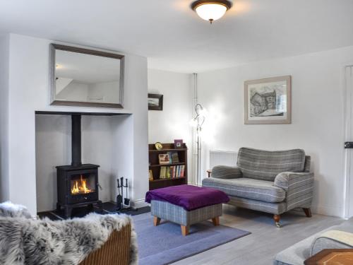 a living room with a fireplace and a couch and a chair at The Old Cottage in Coanwood