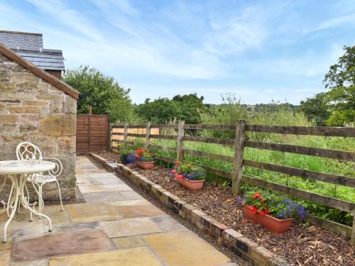 a patio with a table and potted plants on a fence at The Old Cottage in Coanwood