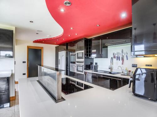 a kitchen with a red ceiling and a red counter top at Sir A Wel in Llanerchymedd