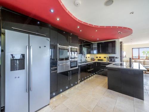 a kitchen with black cabinets and a red ceiling at Sir A Wel in Llanerchymedd