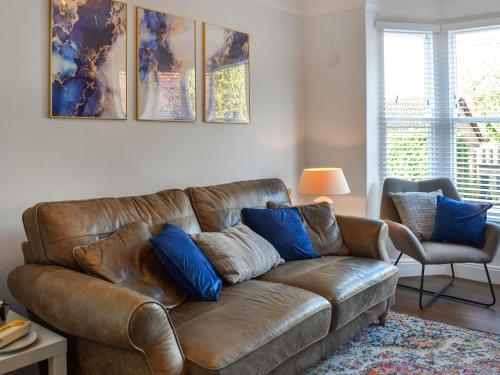 a brown leather couch in a living room with blue pillows at Mere Walk in Hornsea