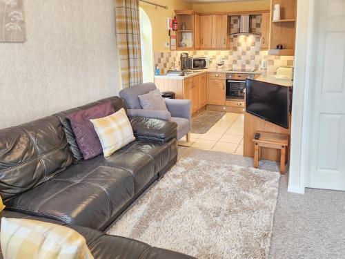 un soggiorno con divano in pelle e cucina di 4 Eldin Hall Cottages a Cayton