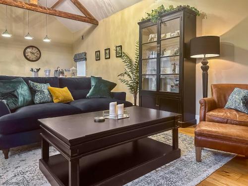 a living room with a blue couch and a coffee table at Sykelands Cottage in Ravensworth