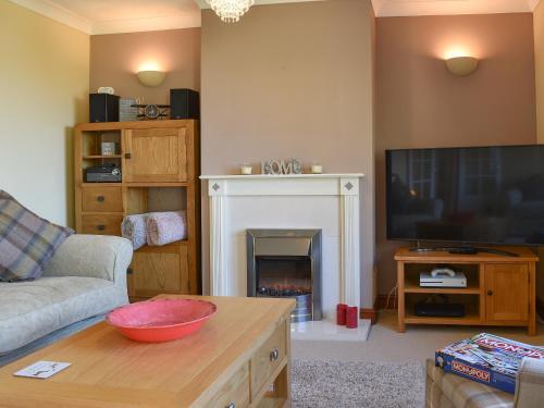 a living room with a fireplace and a television at The Orchard in Bideford