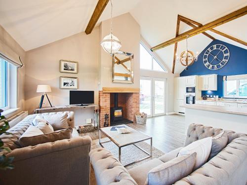 ein Wohnzimmer mit Sofas und einer Uhr an der Wand in der Unterkunft Carmel in Beadnell