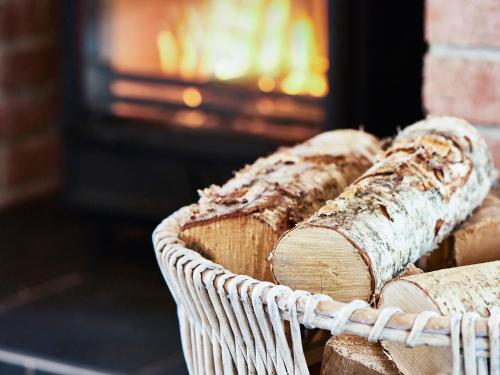ein Korb mit Holzscheiten vor einem Kamin in der Unterkunft Carmel in Beadnell