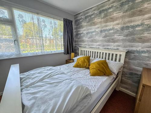 a bedroom with a bed with white sheets and yellow pillows at Beautiful Chalet With Free Wifi Nearby Hemsby Beach In Norfolk Ref 59096S in Hemsby