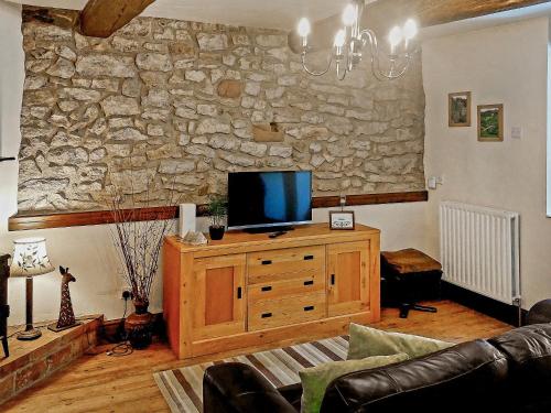 a living room with a tv and a stone wall at The Miners Rest in Middleton