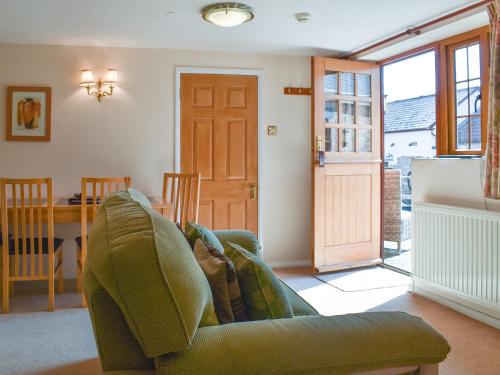 a living room with a green couch and a table at The Dairy in Sidbury