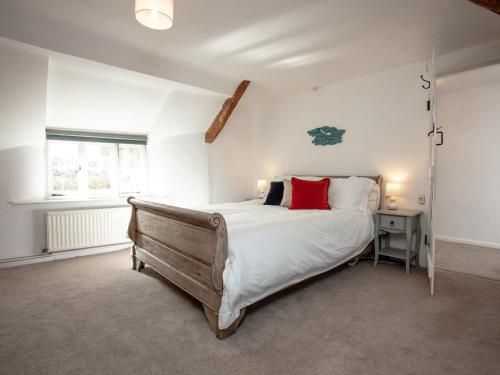 a bedroom with a bed with white sheets and red pillows at The Old Farmhouse in South Chard