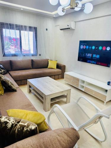 a living room with a couch and a table and a tv at Soman Gueliz Center Apartment in Marrakech