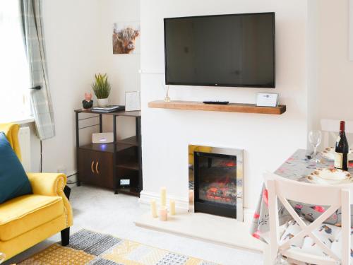 Wellwood Cottage في موربيث: غرفة معيشة مع موقد وتلفزيون فوقها