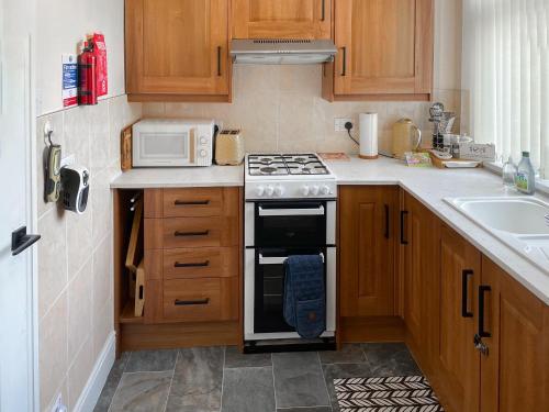 a kitchen with a stove and a microwave at Wellwood Cottage in Morpeth