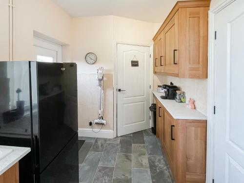a kitchen with a black refrigerator and wooden cabinets at Wellwood Cottage in Morpeth