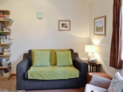 ein Wohnzimmer mit einem blauen Sofa und grünen Kissen in der Unterkunft Rose Cottage - W41462 in Sturminster Newton
