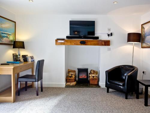 a living room with a desk and a tv and a fireplace at Devon Villa Garden Apartment in Torquay