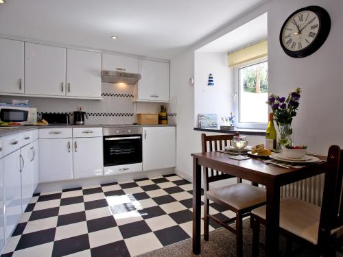 a kitchen with a table and a clock on the wall at Devon Villa Garden Apartment in Torquay