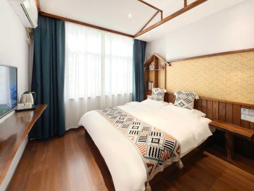 Un dormitorio con una cama grande y una ventana. en Xiaobeilou Inn Zhangjiajie Railway Station Tianmen Mountain Cableway Branch, en Zhangjiajie
