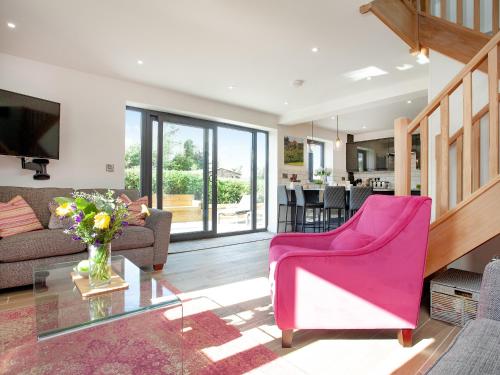 a living room with a pink chair and a glass table at Brook Cottage-Uk44378 in Washford
