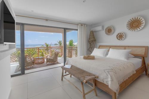 a bedroom with a large bed and a balcony at Villa Baya in Oyster Pond