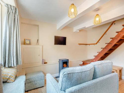 a living room with a blue couch and a staircase at Duckling Cottage in Addingham