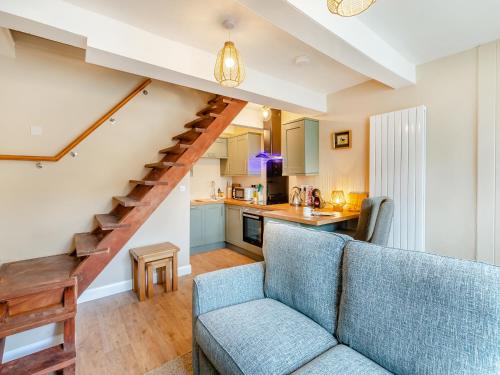 a living room with a blue couch and a kitchen at Duckling Cottage in Addingham