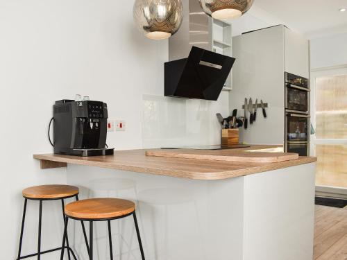 a kitchen with two bar stools and a microwave at The Dawn in Looe