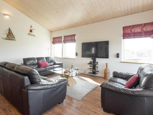 a living room with leather furniture and a flat screen tv at Broad Reach - 28121 in Fritton Norfolk